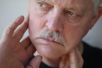 man checking for lumps on neck and jaw